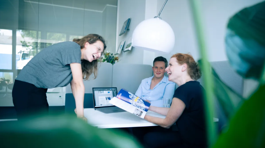 Kolleginnen und Kollegen lachen bei einer Besprechung